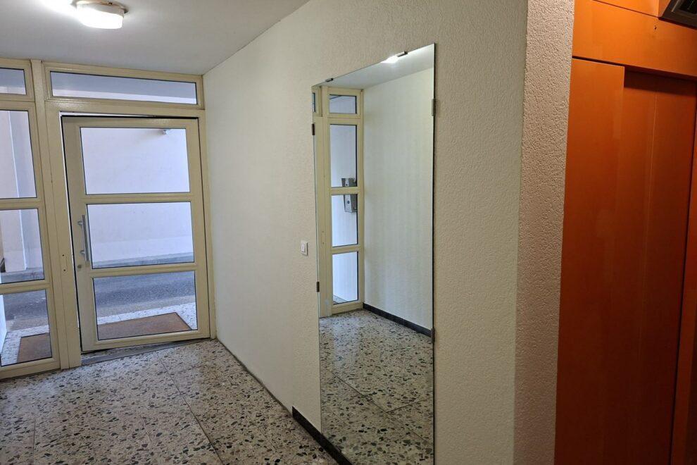 Hall d'entrée d'immeuble repeint, porte d'ascenseur orange