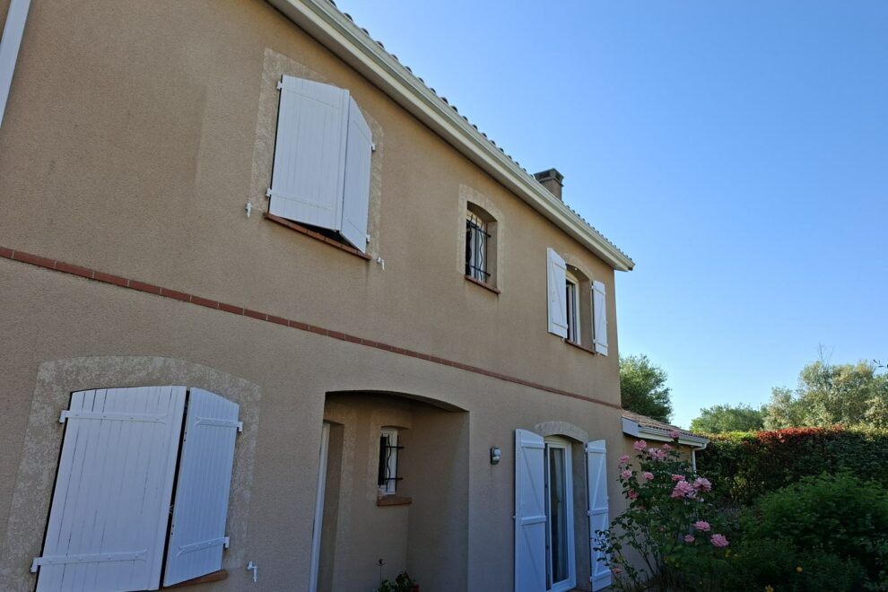 Façade de maison enduite et volets battants blancs après rénovation