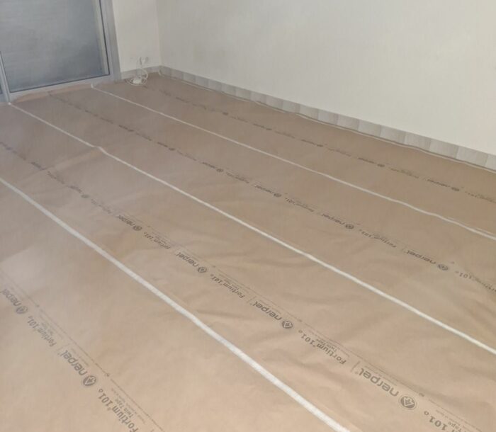 Sol d'appartement entièrement protégé par du papier de protection avant les travaux de peinture