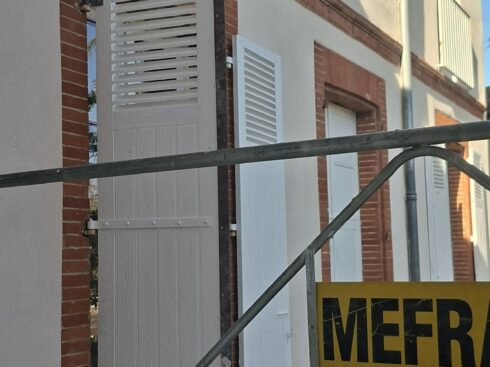 Façade de brique de l'immeuble et volets, échafaudage en place