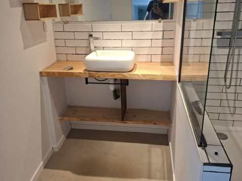 Meuble vasque en bois et étagères murales dans la salle de bain rénovée