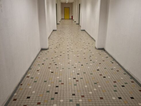 Rénovation de couloirs à Pamiers : long couloir blanc, portes colorées et sol en mosaïque